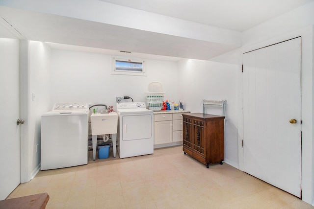 clothes washing area with light floors, a sink, and independent washer and dryer