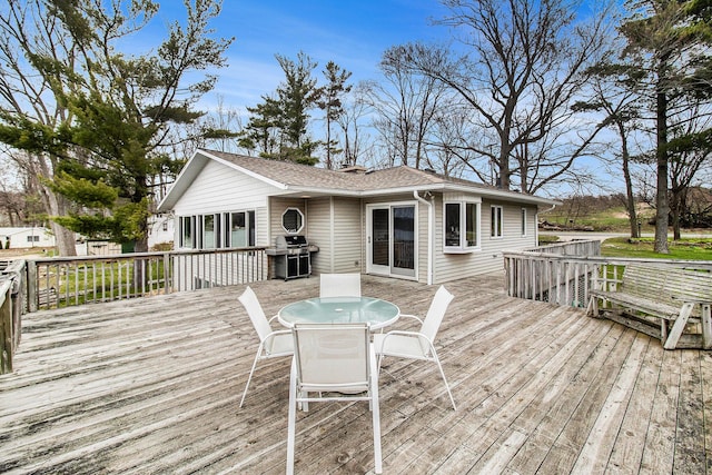 wooden deck with outdoor dining space and area for grilling