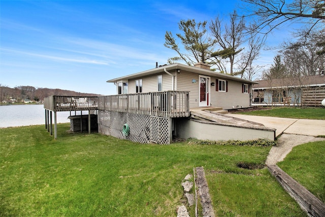 view of front of property with a chimney, a deck with water view, and a front yard