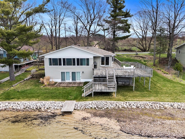 rear view of house with stairway, a wooden deck, and a lawn