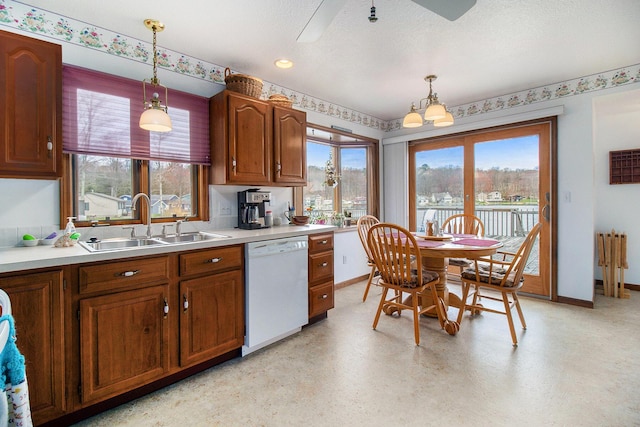 kitchen with dishwasher, baseboards, a sink, and hanging light fixtures