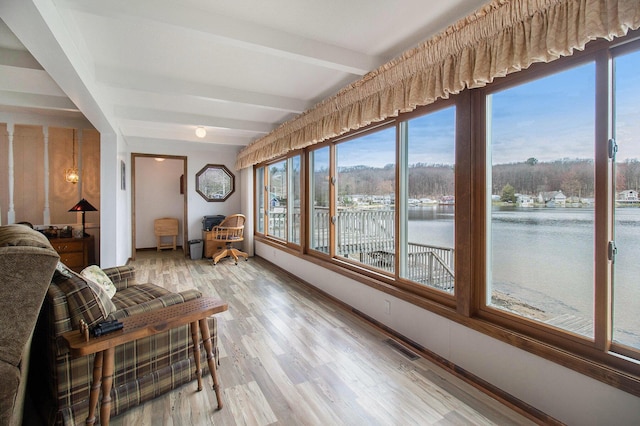 sunroom with visible vents, wood finished floors, beamed ceiling, and a water view
