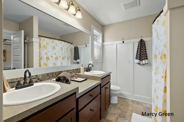 full bathroom featuring double vanity, visible vents, stone finish flooring, and a sink