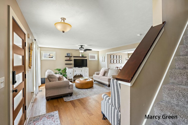 living room with light wood-style flooring, stairs, and ceiling fan