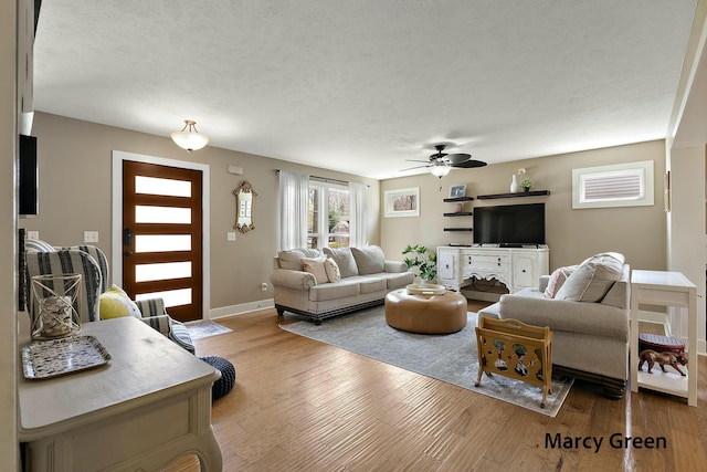 living room with baseboards, wood finished floors, a textured ceiling, and ceiling fan