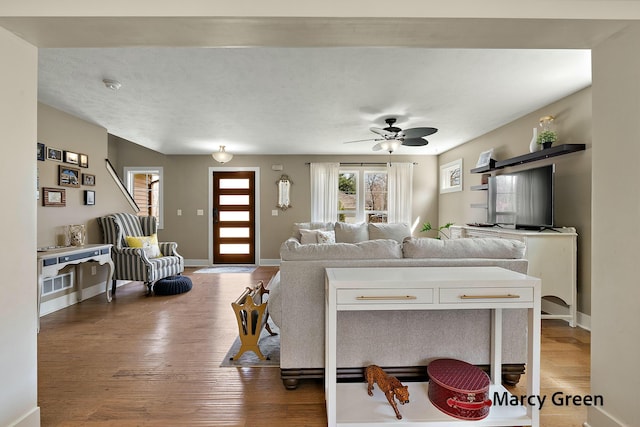 living room featuring light wood-style floors, baseboards, and ceiling fan
