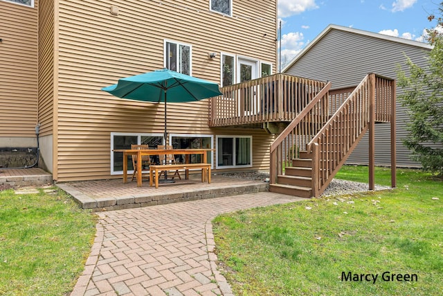 back of property with a lawn, a wooden deck, stairway, and a patio