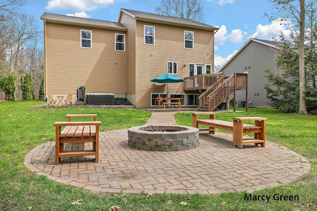 rear view of house with stairway, a wooden deck, a patio, a lawn, and a fire pit