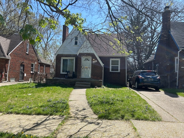 view of front of house featuring a chimney, a front lawn, and brick siding