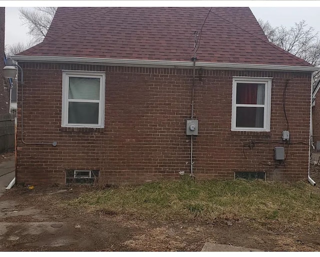 view of side of property featuring brick siding and a shingled roof