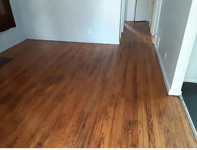 unfurnished room with dark wood-type flooring and baseboards