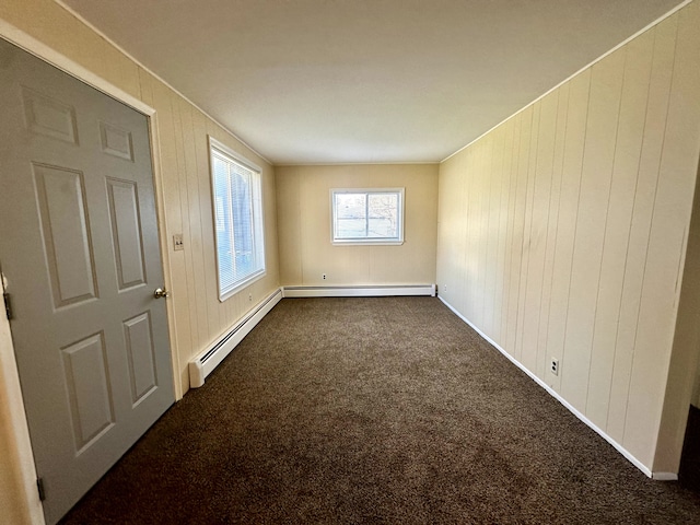 spare room featuring a baseboard radiator, baseboards, and dark colored carpet