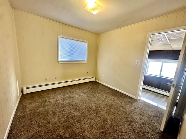 unfurnished room with a baseboard heating unit and carpet floors