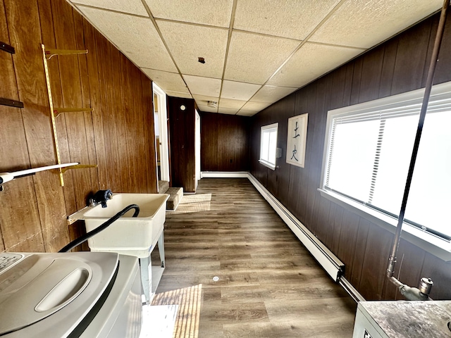 interior space featuring a baseboard radiator, wood walls, wood finished floors, and laundry area