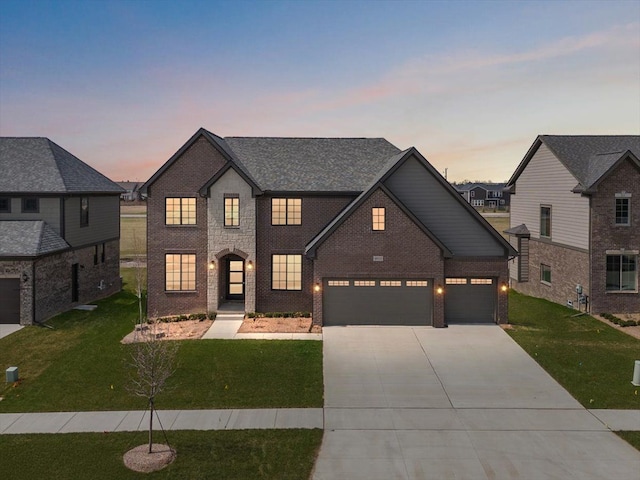traditional-style home featuring a lawn, an attached garage, driveway, and brick siding
