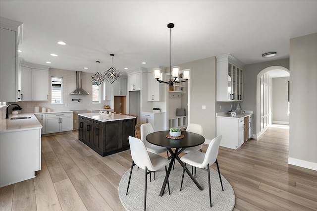 dining area with recessed lighting, arched walkways, light wood-type flooring, baseboards, and a chandelier