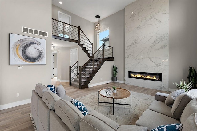 living room with a fireplace, wood finished floors, visible vents, and baseboards