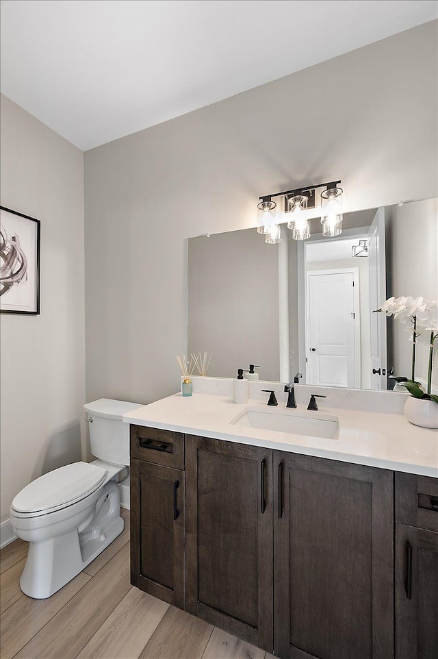 bathroom with toilet, vanity, and wood finished floors
