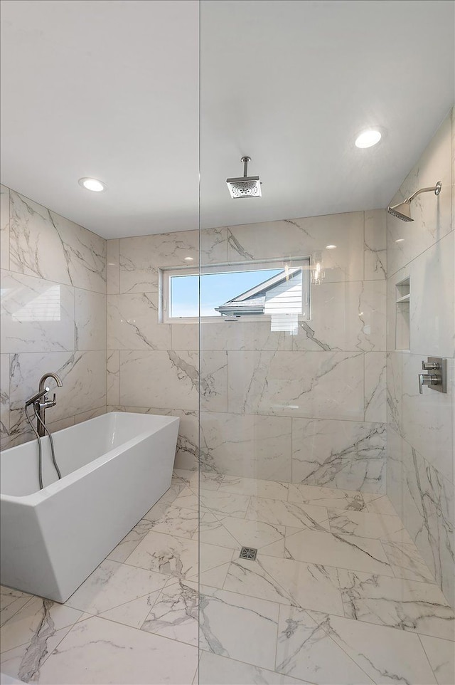 full bath with a freestanding tub and a marble finish shower