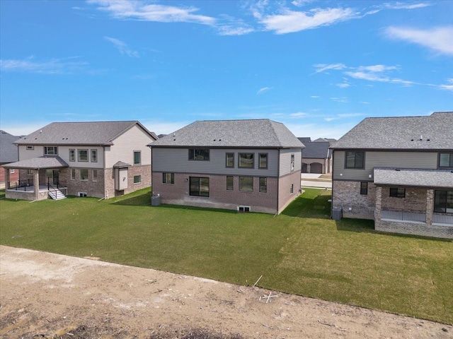 back of property featuring brick siding, a yard, and a residential view