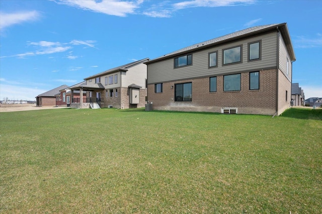 rear view of property with a lawn, brick siding, and central AC