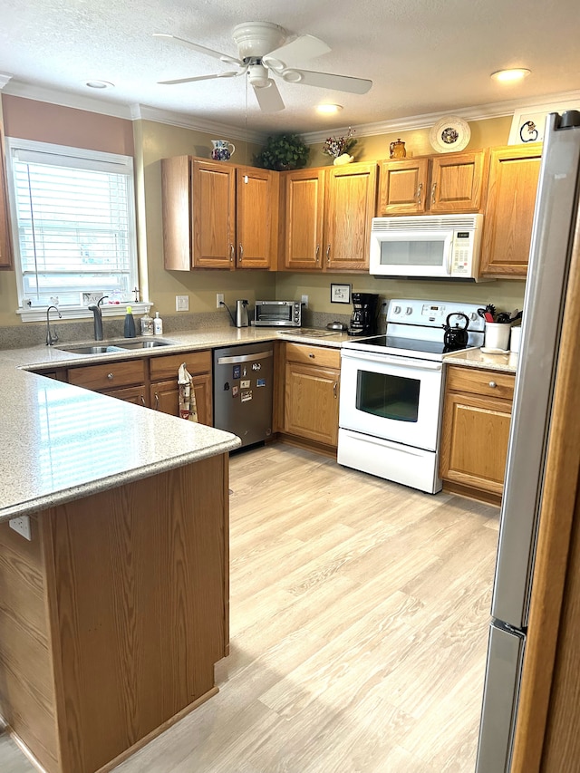 kitchen featuring light countertops, appliances with stainless steel finishes, a sink, and light wood finished floors