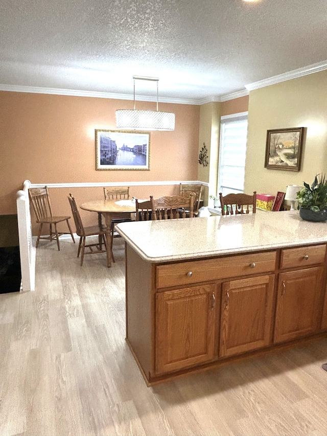 kitchen with brown cabinetry, a textured ceiling, light wood-type flooring, ornamental molding, and a breakfast bar