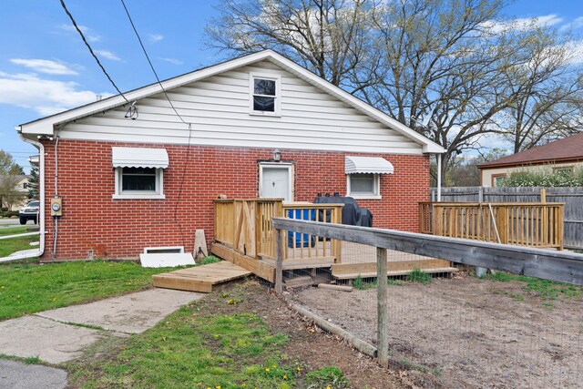 1401 S Williams Lake Rd, Waterford, MI 48327 - back of property with brick siding, a wooden deck, fence, and heating fuel