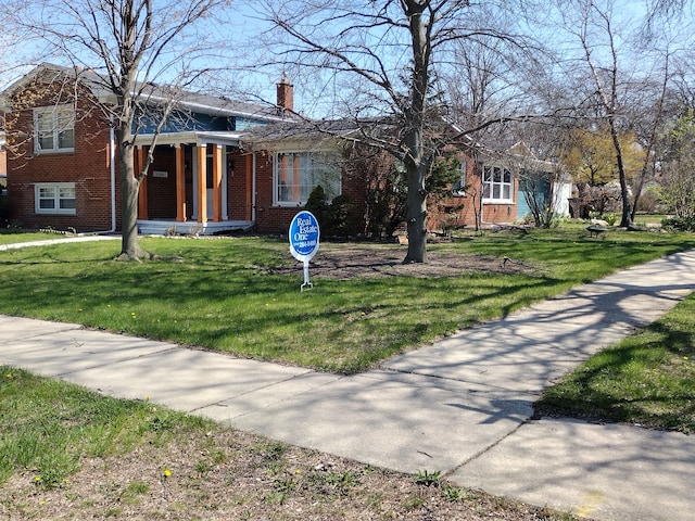 1981 Westfield Rd, Trenton, MI 48183 - view of front of house with a porch, a front lawn, brick siding, and a chimney