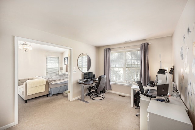 office space featuring a healthy amount of sunlight, baseboards, a chandelier, and light carpet