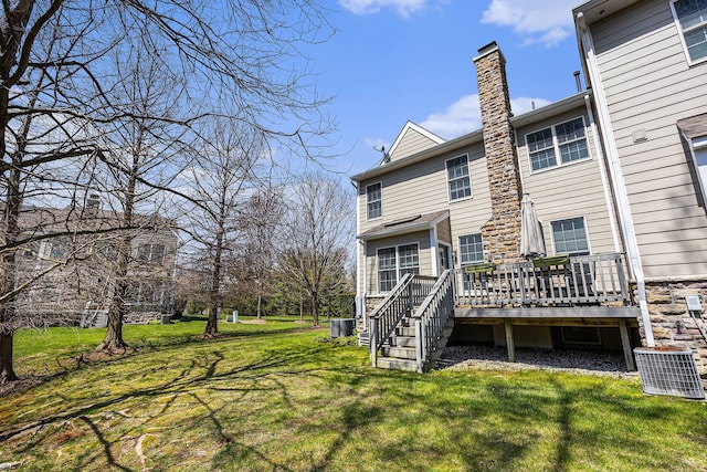 rear view of house with a lawn, a wooden deck, central air condition unit, and a chimney