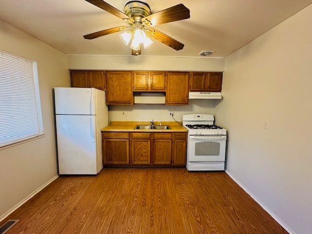 819 Frank Ave, Lincoln Park, MI 48146 - kitchen featuring white appliances, under cabinet range hood, brown cabinets, a sink, and visible vents