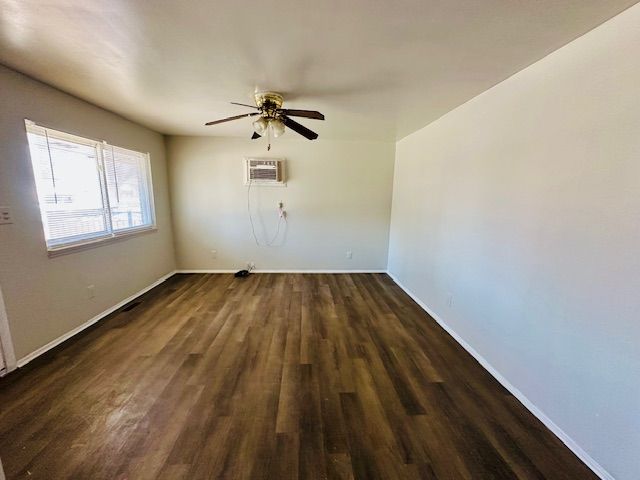 819 Frank Ave, Lincoln Park, MI 48146 - spare room with ceiling fan, baseboards, a wall mounted AC, and dark wood-type flooring
