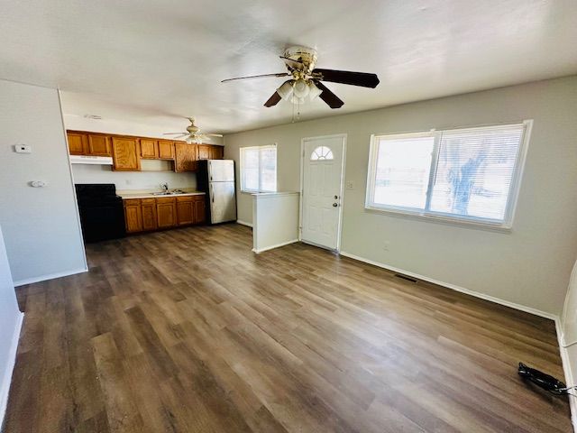 819 Frank Ave, Lincoln Park, MI 48146 - kitchen with dark wood-style floors, ceiling fan, brown cabinetry, baseboards, and freestanding refrigerator