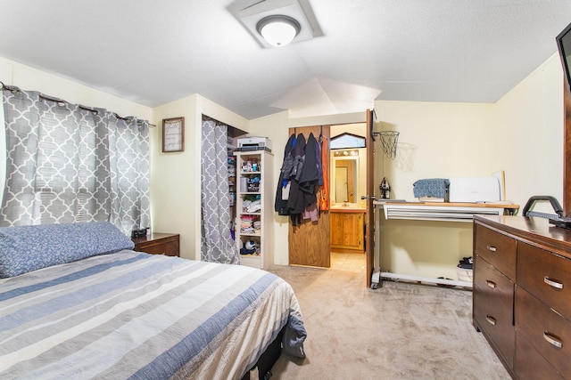 bedroom with lofted ceiling, ensuite bath, and light colored carpet