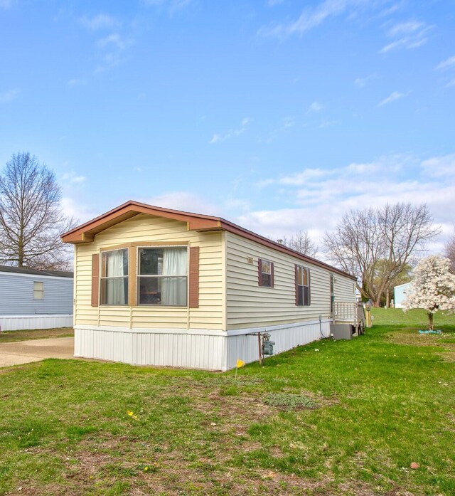 view of side of property with central AC and a yard