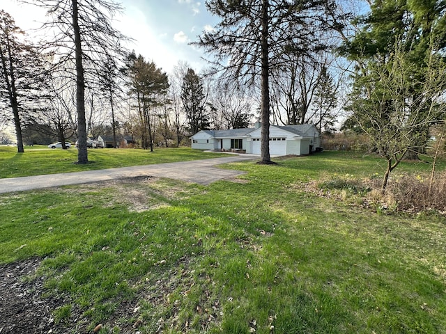 view of yard featuring an attached garage and driveway
