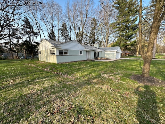 back of property featuring a yard, an attached garage, and a chimney
