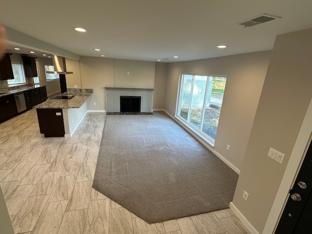 unfurnished living room with baseboards, a brick fireplace, visible vents, and recessed lighting