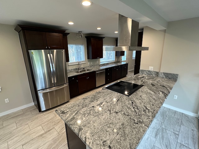 kitchen featuring stainless steel appliances, a sink, baseboards, island range hood, and light stone counters
