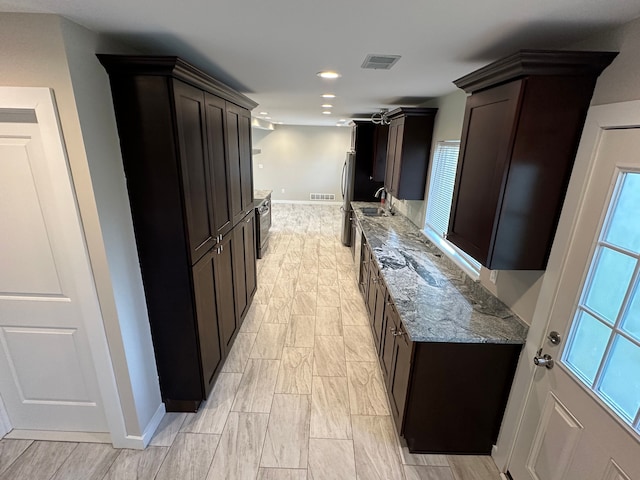 kitchen featuring dark brown cabinetry, light stone counters, visible vents, and recessed lighting