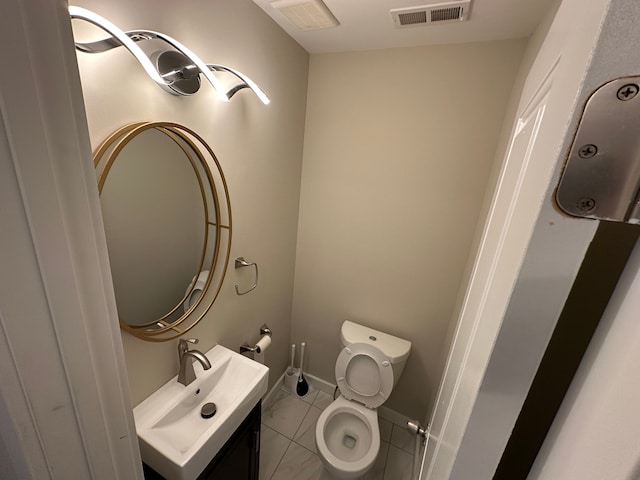 bathroom with toilet, vanity, visible vents, and baseboards