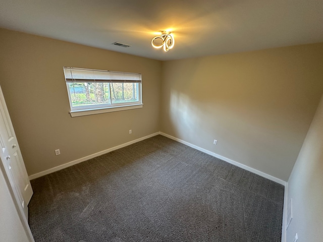 unfurnished room featuring dark carpet, baseboards, and visible vents
