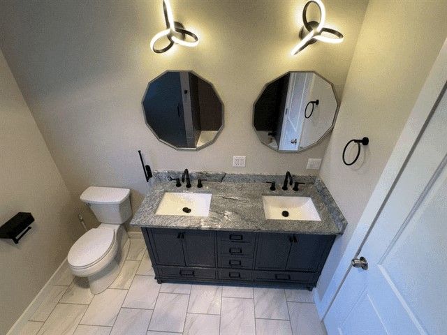 bathroom with a sink, double vanity, and toilet