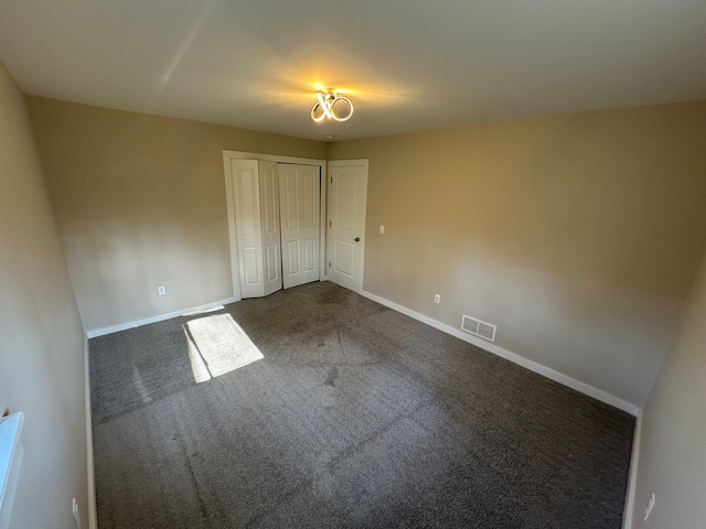 unfurnished bedroom featuring a closet, dark colored carpet, visible vents, and baseboards