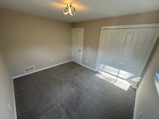 unfurnished bedroom with baseboards, visible vents, carpet floors, and a closet