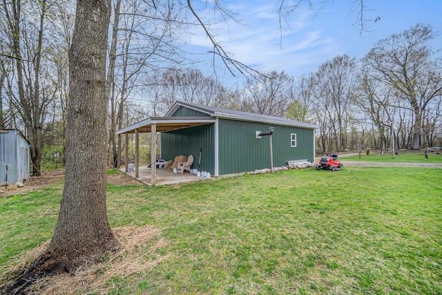 view of home's exterior with a patio area, a lawn, and an outbuilding