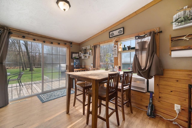 dining room with lofted ceiling, visible vents, and wood finished floors