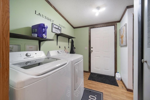 laundry area featuring laundry area, light wood-style floors, crown molding, separate washer and dryer, and a textured ceiling