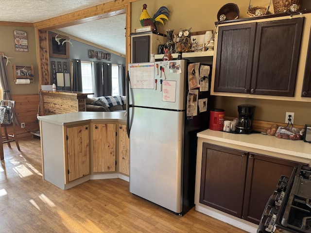 kitchen featuring a peninsula, freestanding refrigerator, vaulted ceiling, and light countertops